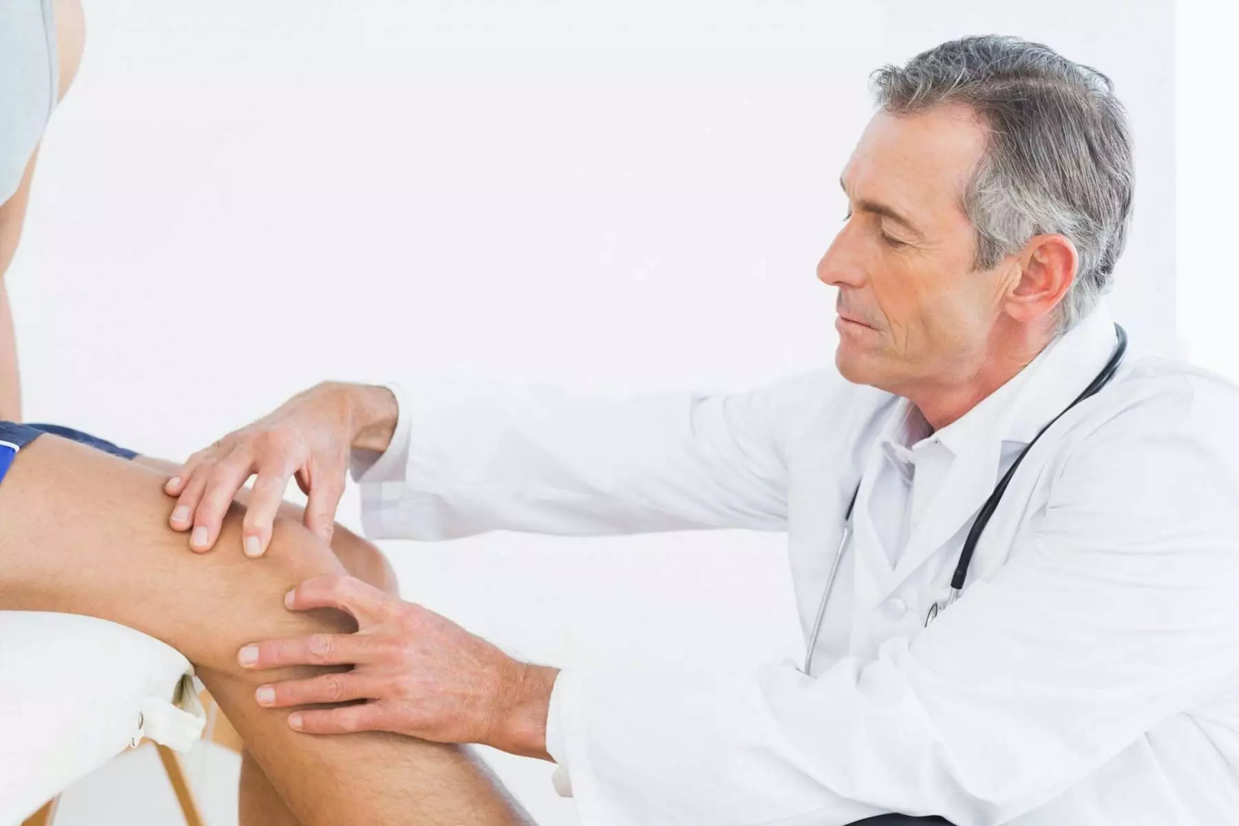 Doctor examining a patient experiencing leg pain.