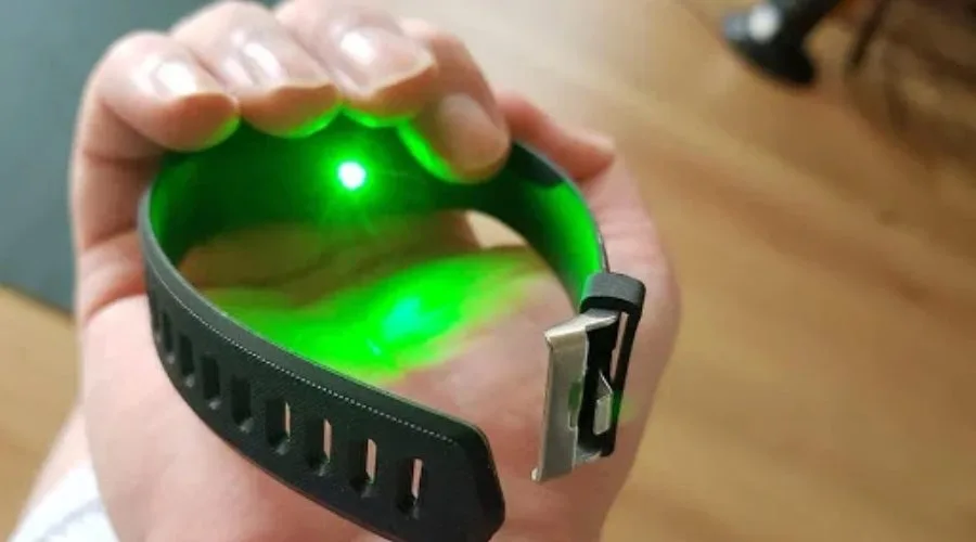 Une personne tenant dans sa main la montre SmartTrack, montrant le laser vert à l'arrière de la montre qui mesure la tension.
