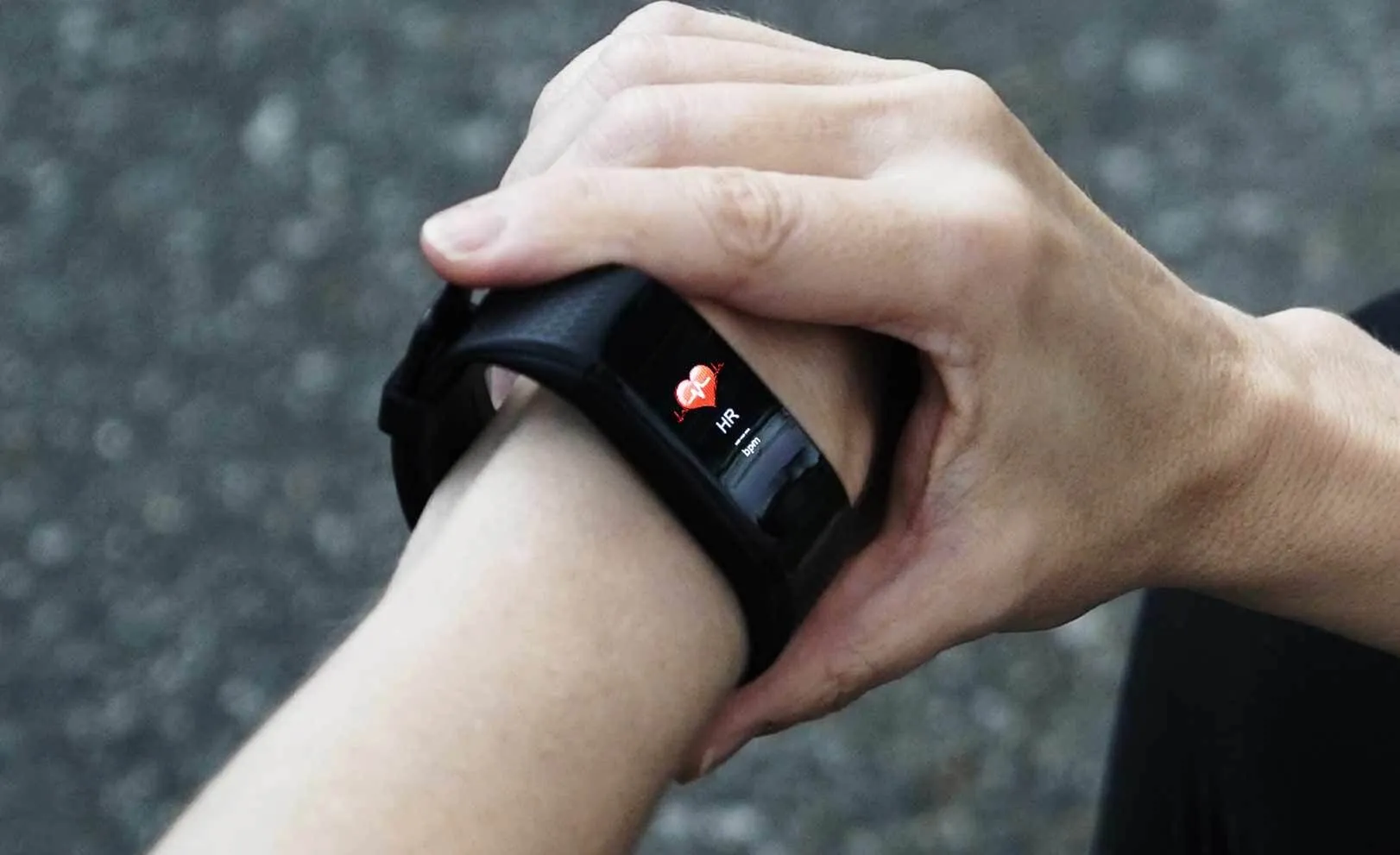 Le bras d'une personne portant une montre SmartTrack au poignet, avec un écran affichant un cœur rouge.